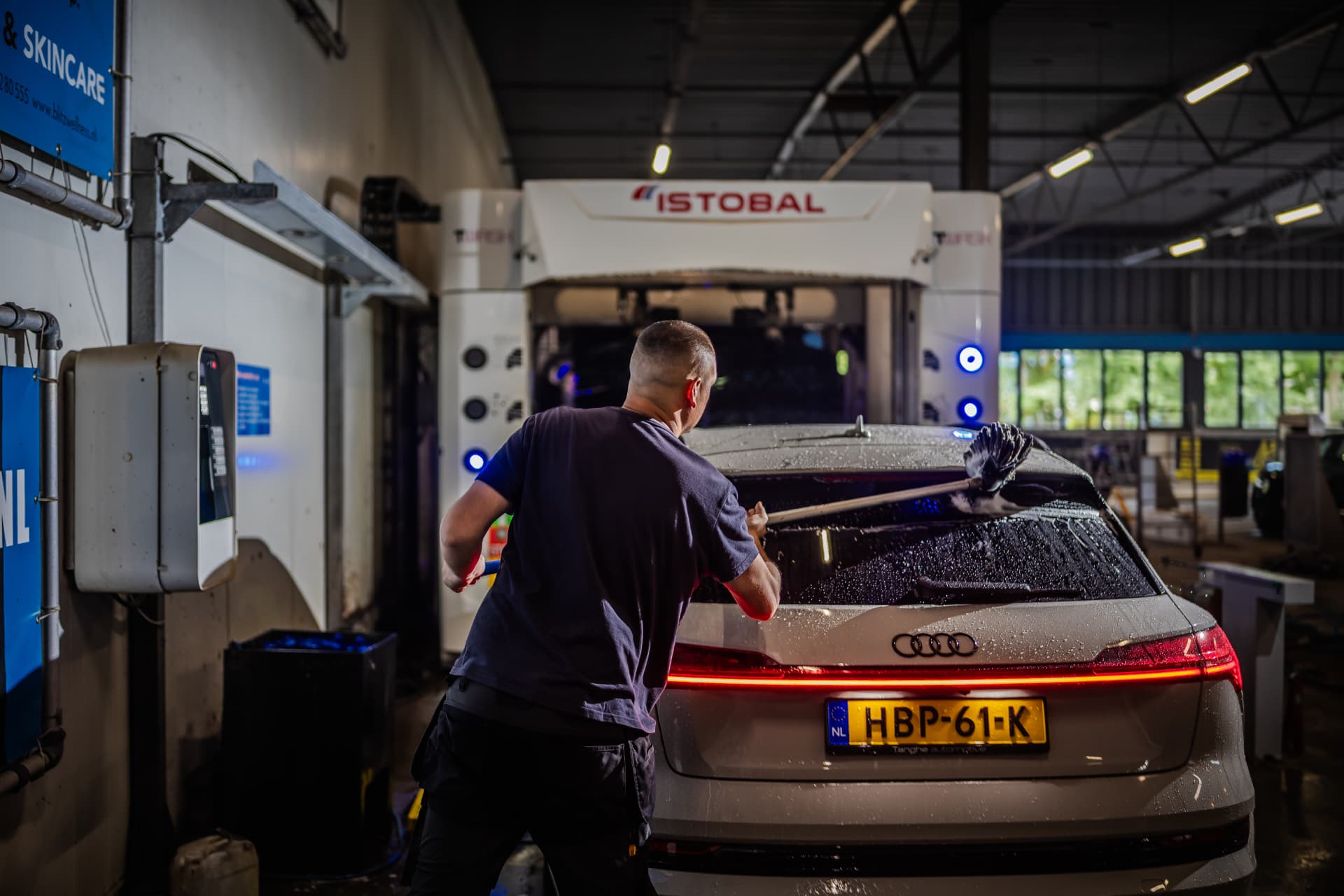 Medewerker droogt en poetst een auto na de wasbeurt