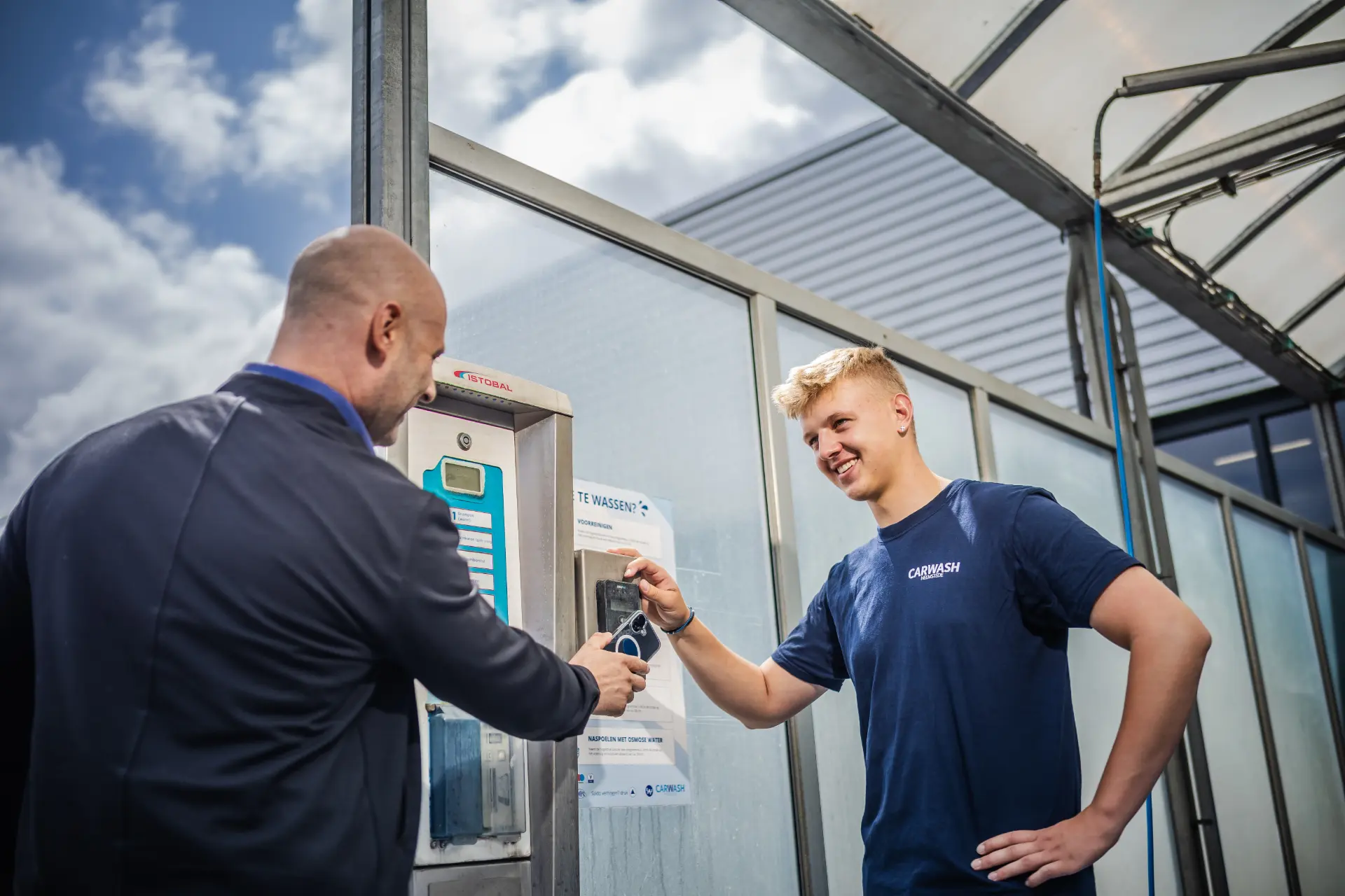 Medewerker van Carwash Heemstede helpt een klant bij de betaalzuil